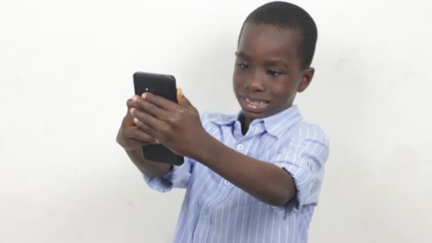 Kleine Jongen Die Met Een Mobieltje Een Witte Achtergrond Speelt — Stockvideo