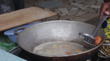 Mavi elbiseli olgun bir kadın bir sandalyede oturmuş un topları yapıyor.
