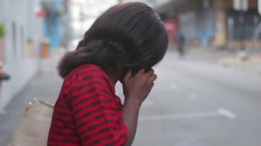 Güzel, olgun bir kadın geleneksel elbiseleriyle dışarıda duruyor ve cep telefonuyla şarkı söylüyor..