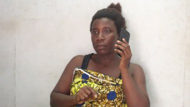 Güzel bir kadın evde oturmuş cep telefonu kullanıyor.