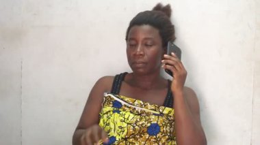 Güzel bir kadın evde oturmuş cep telefonu kullanıyor.