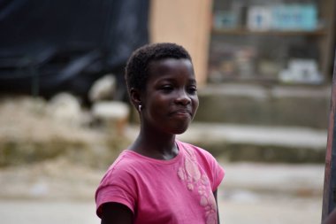 Dışarıda durup kameraya bakan gülümseyen kızın portresi..