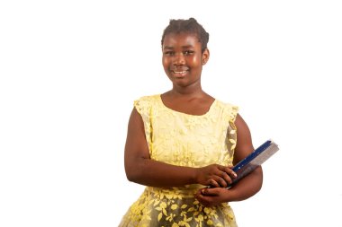 Beyaz arka planda duran genç kız öğrenci elinde kitapla kameraya bakıp gülümsüyor..