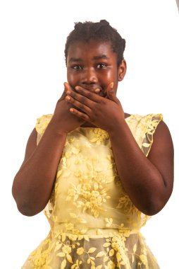 Güzel, genç bir kız beyaz arka planda durup elleri ile ağzını kapatan bir şeye bakıyor..