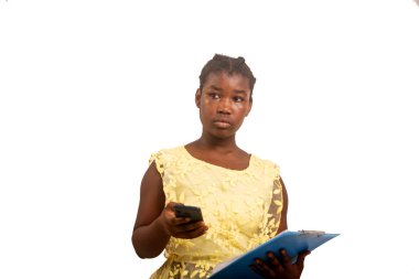 Beyaz arka planda duran sarı bluzlu güzel bir bayan öğrenci elinde belge ve cep telefonu tutarken düşünüyor..