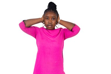 Pembe gecelikli genç kız sağır edici gürültüden kaçınmak için beyaz arka planda durup kulaklarını ellerinle kapatıyor..