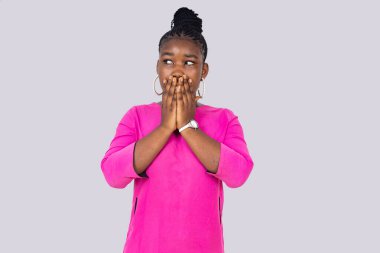 Beyaz bir arka planda duran pembe gecelikli genç bir kız şaşırmış bir bakışla başka tarafa bakıyor..