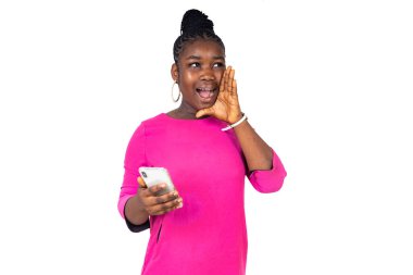 Pembe gecelikli genç bir kız beyaz bir arka planda duruyor cep telefonuyla elini ağzına koyup çığlık atıyor..