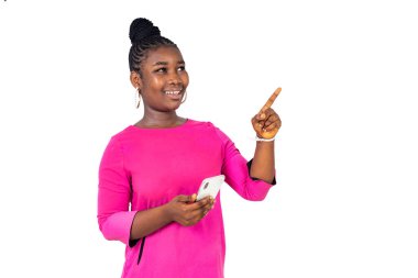 Pembe gecelikli genç bir kız beyaz bir arka planda cep telefonuyla gülüyor..