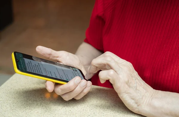 The phone is in the hands of an elderly woman of retirement age. Smartphone use by the elderly. High quality photo