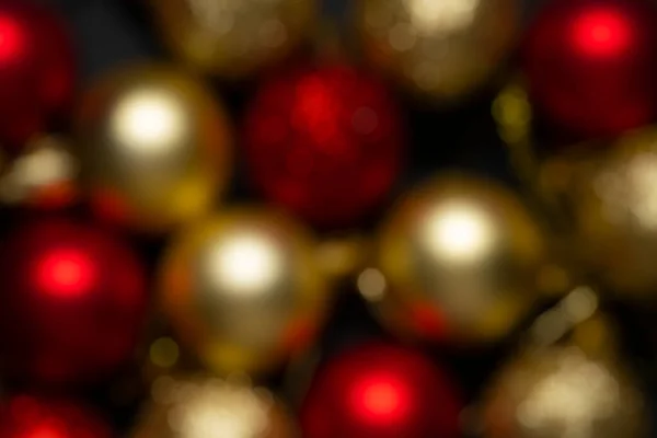 Christmas balls of red and gold color in blur on a black background. Christmas background without focus, screensaver. High quality photo