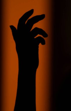 Siluet, batan güneşin turuncu ışınlarında duvarda bir kadının elinin gölgesi. Görüntü olarak soyut arkaplan, odak dışı. Yüksek kalite fotoğraf