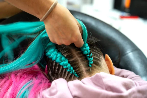 Bir kız için parlak pembe ve mavi kanekalondan moda örgüler örme süreci. Okula dönelim. Braid stüdyosu. Yüksek kalite fotoğraf
