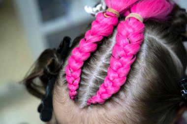 Bir kız için parlak pembe ve mavi kanekalondan moda örgüler örme süreci. Okula dönelim. Braid stüdyosu. Yüksek kalite fotoğraf