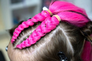 Bir kız için parlak pembe kanekalondan moda örgüler örme süreci. Okula dönelim. Braid stüdyosu. Yüksek kalite fotoğraf