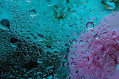 Arka planda bulanıklık var, camda su damlaları var. Kartpostal, kapak, hikâye arka planı için pembe, akuamarin ve yeşil renklerde soyut bir arkaplan. Yüksek kalite fotoğraf