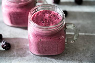 Gri arka planda böğürtlen suyu olan iki kupa. Sağlıklı bir diyet için lezzetli bir tatlı. Yakın plan..