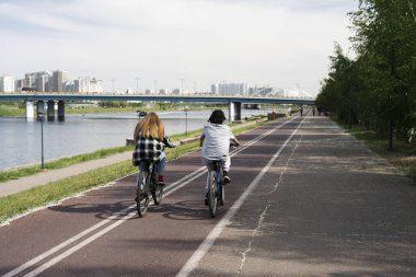 Nur-Sultan, Kazakistan, Haziran 2022. İki genç kız şehrin seddi boyunca bisiklet sürüyor.. 