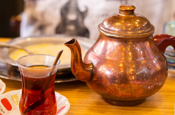 Turkish tea in a transparent cup and teapot in the background. High quality photo