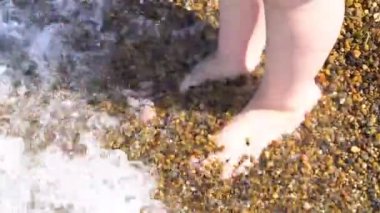 Dalgalar çocukların ayaklarını kıyıda yıkar..