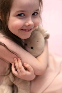 Bir kız, elinde peluş bir tavşanla yedi yıllık bir esmer. Yüksek kalite fotoğraf