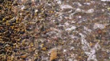 Dalgalar çakıl taşlı kıyıları yıkar. Yüksek kaliteli FullHD görüntüler
