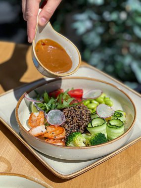 Kız sosu karides, kinoa, brokoli ve fasulyeli bir kaseye döküyor. Faydalı diyet yemekleri, sağlıklı yiyecekler. Yüksek kalite fotoğraf