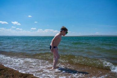 Dalış maskesi takmış 7 yaşında bir çocuk sahile yakın bir yerde duruyor. Yüksek kalite fotoğraf