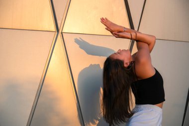 Genç Asyalı kadın gündüz vakti şehir manzarasıyla yoga yapıyor. Şehir yogası, gün doğumu egzersizi. Şehir yogası, gün doğumu egzersizi..