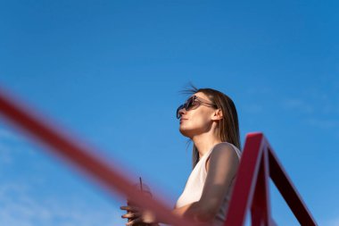 Mavi arka planda güneş gözlüklü esmer bir kadının yaz portresi. Yüksek kalite fotoğraf