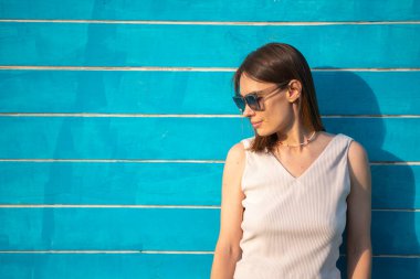Güneş gözlüklü esmer bir kadının yaz portresi mavi ahşap arka planda yazı için yeri olan bir kadına karşı. Yüksek kalite fotoğraf