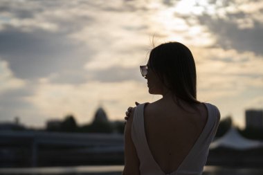 Gün batımına karşı güneş gözlüklü genç bir kadının silueti. Yüksek kalite fotoğraf