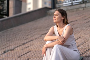 Genç bir kadının yaz şehir portresi. Bir kadın sette oturur ve bir şeyler düşünür. Yüksek kalite fotoğraf