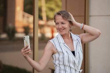 Sarışın genç bir kadın şehir caddesinde selfie çekiyor. Yüksek kalite fotoğraf