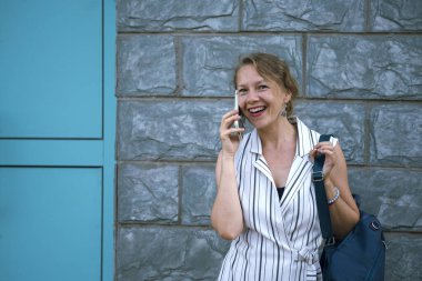 Şehir caddesinde akıllı telefondan konuşan genç sarışın kadın. Yüksek kalite fotoğraf