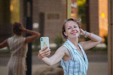 Sarışın genç bir kadın şehir caddesinde selfie çekiyor. Yüksek kalite fotoğraf