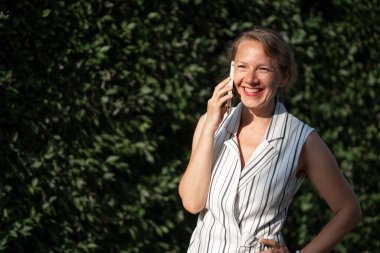 Şehir caddesinde akıllı telefondan konuşan genç sarışın kadın. Yüksek kalite fotoğraf