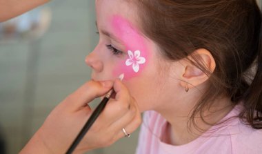 Ressam, kızın yüzüne bir yüz resmi çiziyor. Yüksek kalite fotoğraf