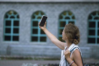 Sarışın genç bir kadın şehir caddesinde selfie çekiyor. Yüksek kalite fotoğraf