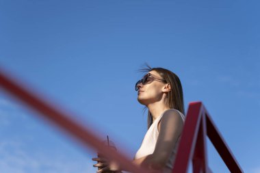 Mavi arka planda güneş gözlüklü esmer bir kadının yaz portresi. Yüksek kalite fotoğraf