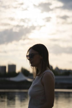 Gün batımına karşı güneş gözlüklü genç bir kadının silueti. Yüksek kalite fotoğraf