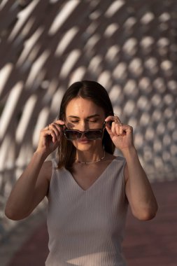 Yazın esmer bir kadının şehir portresi. Kadın güneş gözlüğünü çıkardı. Yüksek kalite fotoğraf