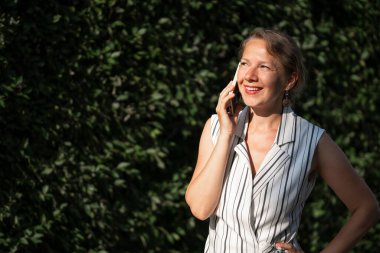 Şehir caddesinde akıllı telefondan konuşan genç sarışın kadın. Yüksek kalite fotoğraf