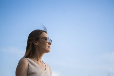 Mavi arka planda güneş gözlüklü esmer bir kadının yaz portresi. Yüksek kalite fotoğraf