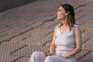 Genç bir kadının yaz şehir portresi. Bir kadın sette oturur ve bir şeyler düşünür. Yüksek kalite fotoğraf