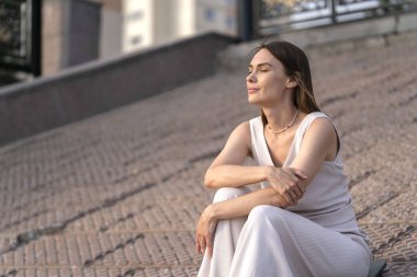 Genç bir kadının yaz şehir portresi. Bir kadın sette oturur ve bir şeyler düşünür. Yüksek kalite fotoğraf