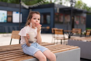 Altı yaşında bir kız milkshake içer ve böbreğini yer. Çocukların hayatında şekerler, sokak yemekleri. Yüksek kalite fotoğraf