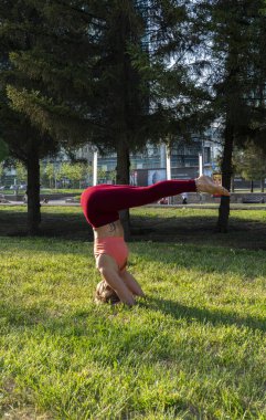 Şehir caddesinde çimlerin üzerinde yoga yapan 59 yaşındaki olgun bir kadının portresi. Yetişkinlerin aktif spor yaşam tarzı. 