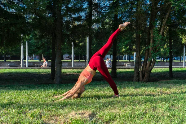 Portrait of a mature woman 59 years old who does yoga on the city street on the lawn. Active sport lifestyle of mature people.