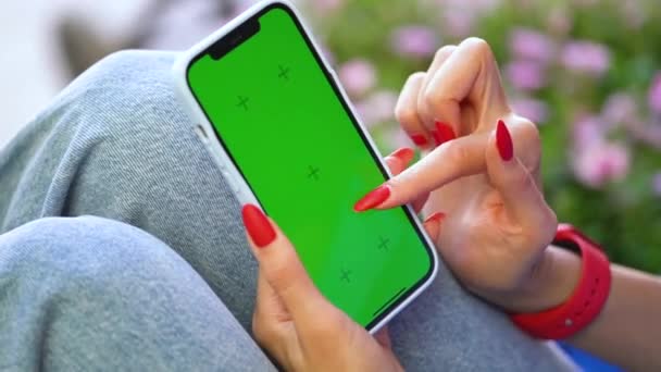 長い赤い爪を持つ少女は 緑色のスクリーンでスマートフォンを保持しています Chromeキーモックアップ 高品質のフルHd映像 — ストック動画
